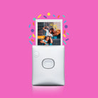 White instant camera with a photo of a couple on a pink background